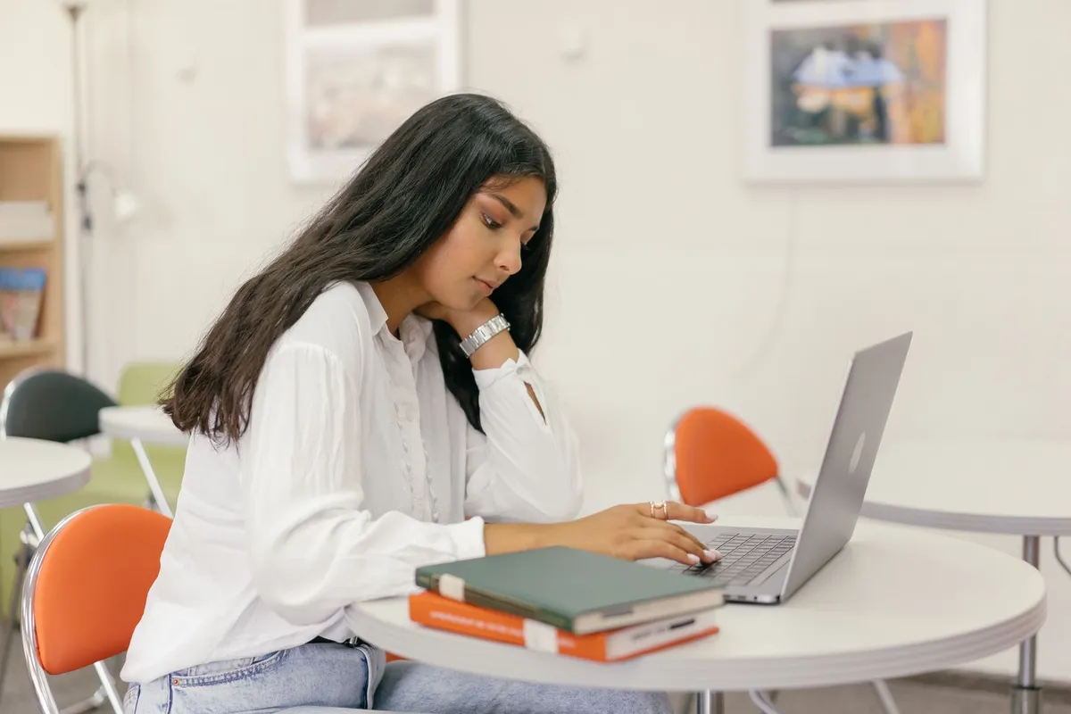 A young woman taking a test on a laptop in a classroom