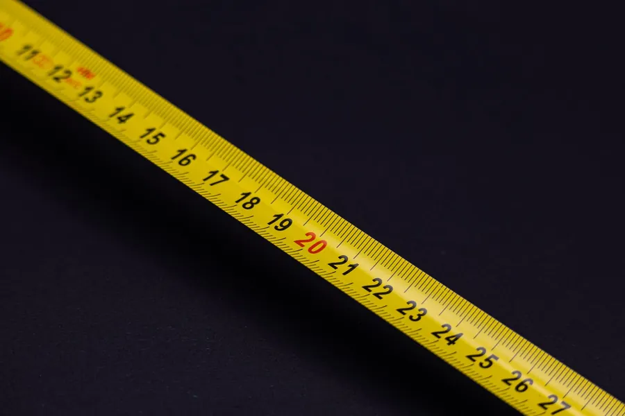 Close-up of a yellow measuring tape showing its numbered scale against a black background